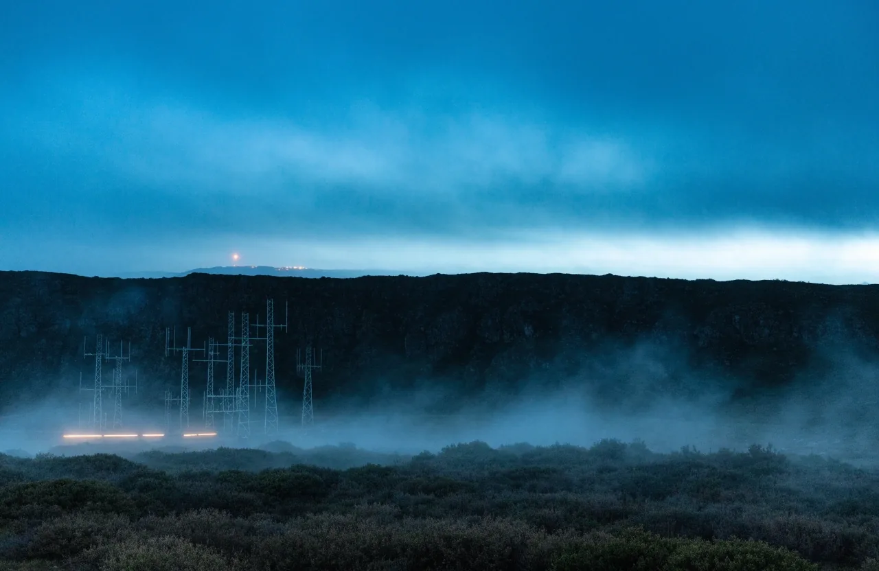 Antenna array on a fogged hill at night against a deep sky